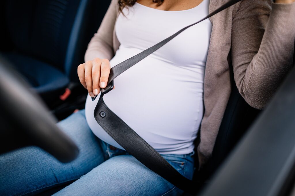 Close de mulher grávida colocando o sinto de segurança