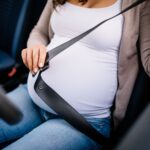 Close de mulher grávida colocando o sinto de segurança