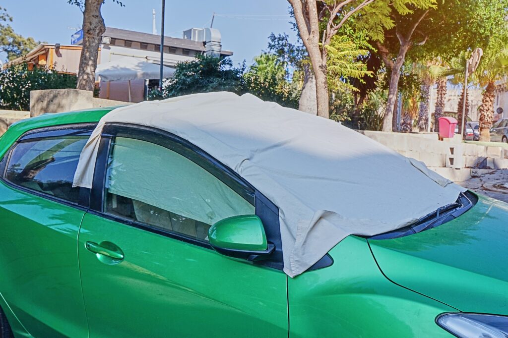 Tecido cobre para-brisa de carro com pintura verde, estacionado no Sol