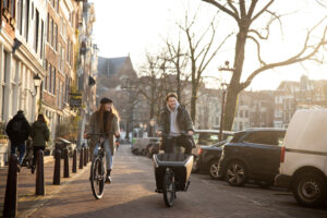 Casal pedalando em rua estreita ao nascer do sol, em um dia frio