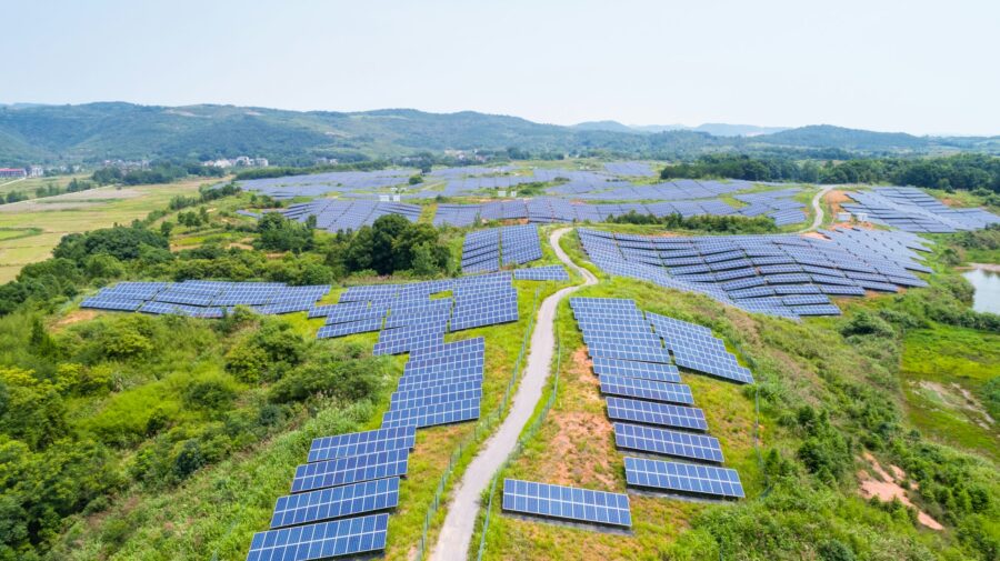 Uma imagem aérea de uma fazenda solar, repleta de painéis fotovoltáicos