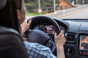 Woman driving a car, hands on the wheel close-up, view from the back to the road.